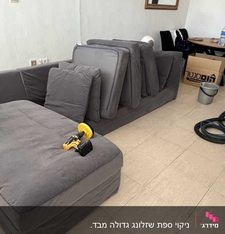 ספה אפורה עם כלי ניקוי ומכונת שאיבה